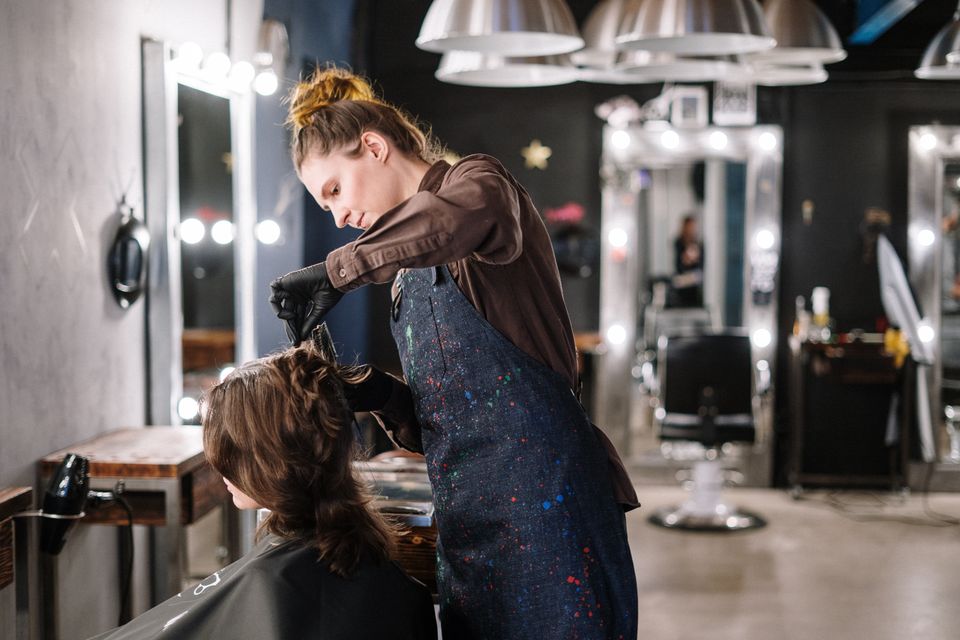 La parrucchiera asciuga i capelli di una cliente nel salone